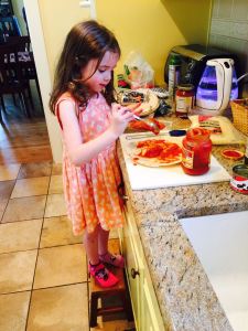 Molly in mismatched socks making her pizza.